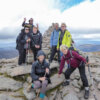 Hiking group poses at the top of one of Scotland's mountain peaks.