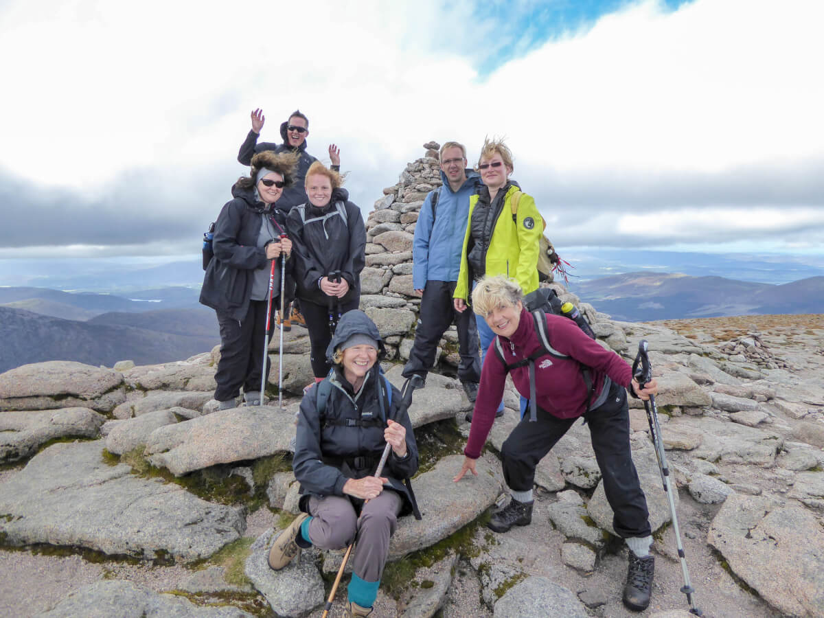 Hiking group poses at the top of one of Scotland's mountain peaks.